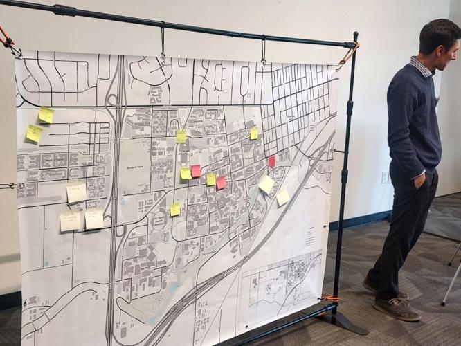 A student stands next to a large display of a map of UC Davis campus and surrounding areas, the map has sticky notes highlighting locations where students gave feedback on transportation.