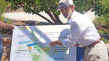 Image of Bob Segar pointing to a board that shows the development of the UC Davis Health Sciences district. 